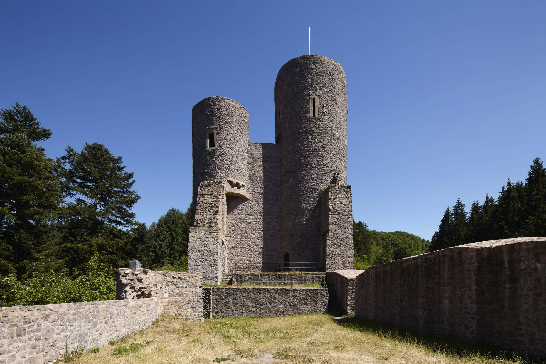 Frauenburg Rundtürme vor blauem Himmel, Mauern und Geländer, dazwischen Wiese, seitlich und im Hintergrund Bäume